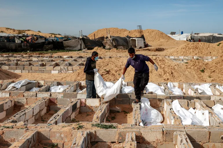 EDITOR'S NOTE: Graphic Content / Men carry a body bag as they bury one of 53 unidentified bodies at a cemetery in Deir el-Balah in the central Gaza Strip on February 13, 2026.