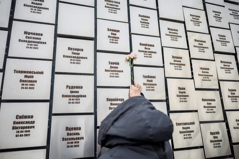 यूक्रेन पर रूस के हमले के बीच, यूक्रेन पर रूस के हमले के बीच, 24 फरवरी, 2026 को यूक्रेन के कीव क्षेत्र के बुचा शहर में, पूर्ण पैमाने पर रूसी आक्रमण की चौथी वर्षगांठ को चिह्नित करते हुए, रूसी सैनिकों द्वारा हमलों और फांसी के पीड़ितों के लिए स्मारक स्थापना पर श्रद्धांजलि देने के लिए एक महिला फूल लाती है। रॉयटर्स/अलीना डेज़।
