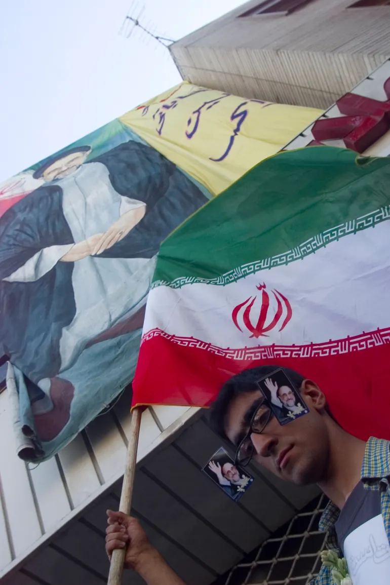 An Iranian with his glasses decorated with photos of President Mohammad Khatami carries national flag during celebration in central Tehran June 9, 2001, a day after country's presidential elections. As Iran's President Mohammad Khatami cruised towards re-election by a landslide on Saturday, supporters urged him to appoint a radical, reformist cabinet to overcome resistance to change by Islamic hardliners. REUTERS/Damir Sagolj (IRAN) BEST QUALITY AVAILABLE