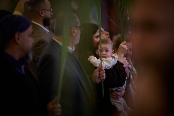 Parishioners hold palm branches during the Palm Sunday celebration at the Our Lady of Hadat Church in Beirut, Lebanon, Sunday, March 29, 2026. (AP Photo/Emilio Morenatti)