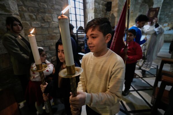 Boys hold candles during Palm Sunday Mass procession at Saint Thomas Cathedral, in the southern port city of Tyre, south Lebanon, Sunday, March 29, 2026. (AP Photo/Hussein Malla)