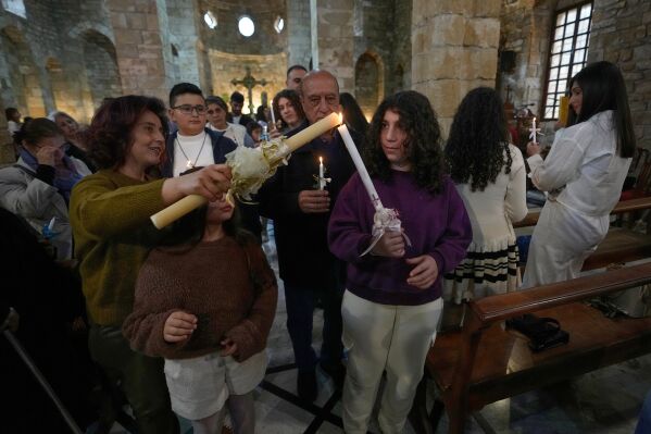 Worshipers light candles as they attend Palm Sunday Mass procession at Saint Thomas Cathedral, in the southern port city of Tyre, south Lebanon, Sunday, March 29, 2026. (AP Photo/Hussein Malla)