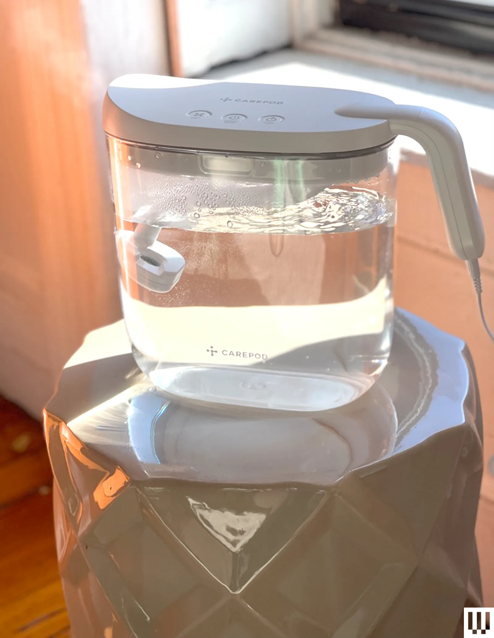 Carepod Mini Humidifier a transparent container with water inside and a slightly curved handle